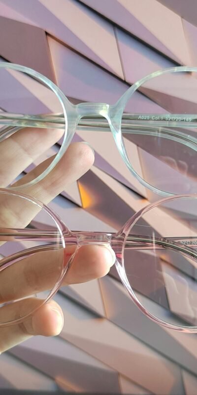 Close-up of two stylish eyeglasses held by a hand against a modern background.