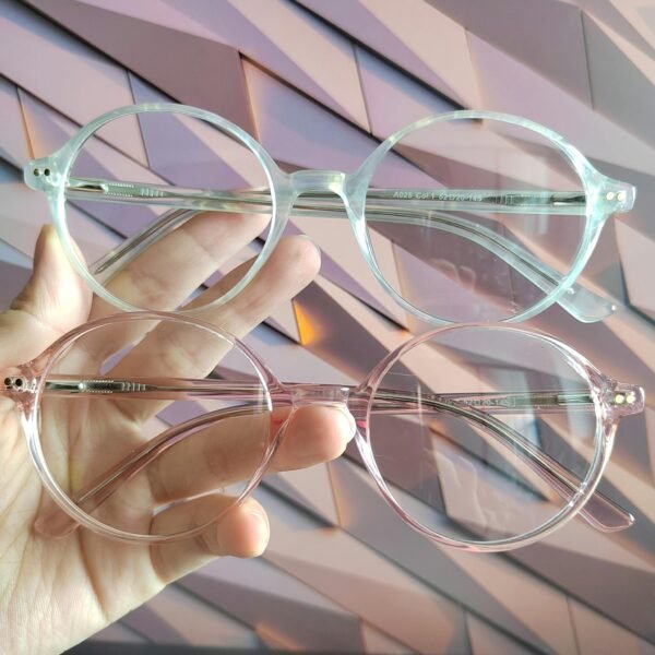 Close-up of two stylish eyeglasses held by a hand against a modern background.
