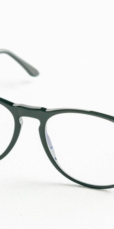 Minimalist close-up of fashionable black eyeglasses on a white surface.