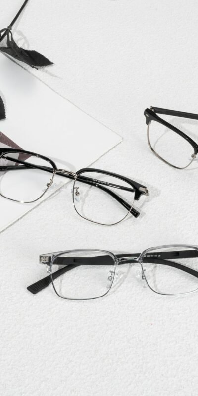 Modern eyewear arrangement with a red rose and stylish magazine backdrop.