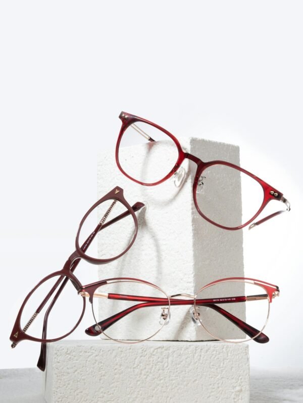 Stylish red and brown eyewear resting on white textured blocks in a minimal studio setup.